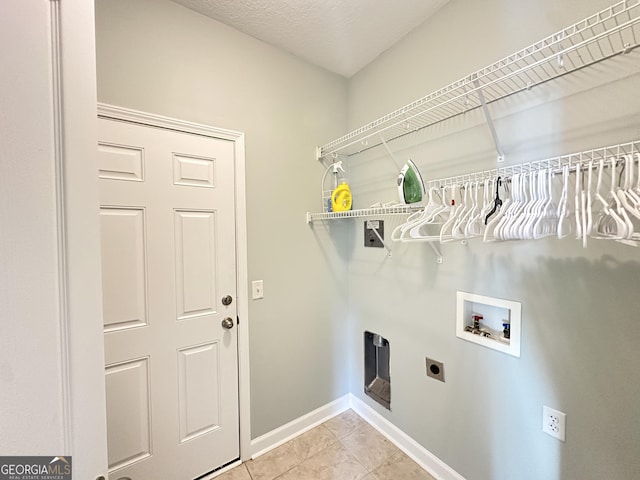 clothes washing area featuring electric dryer hookup, hookup for a washing machine, light tile patterned floors, and a textured ceiling