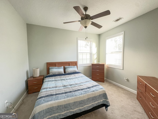 bedroom featuring ceiling fan, light colored carpet, and a textured ceiling