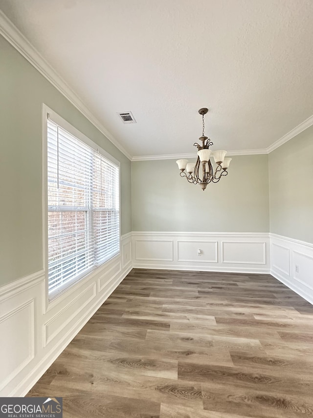 unfurnished dining area featuring crown molding, an inviting chandelier, and hardwood / wood-style flooring