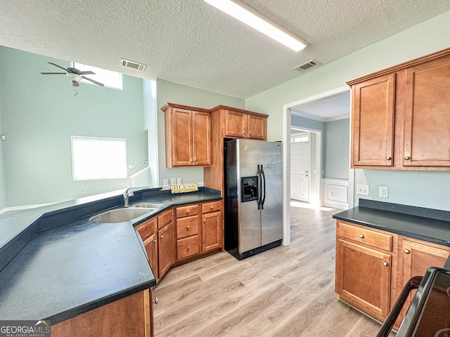 kitchen featuring a textured ceiling, light hardwood / wood-style floors, sink, and stainless steel refrigerator with ice dispenser