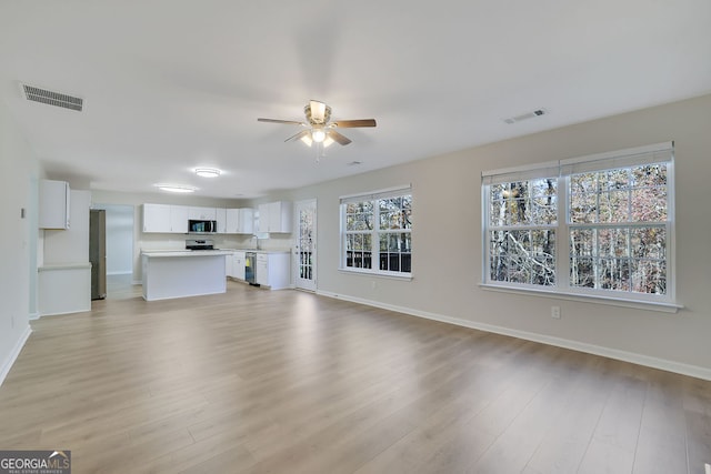 unfurnished living room featuring ceiling fan, light hardwood / wood-style floors, and sink