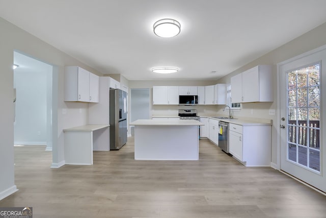 kitchen with white cabinetry, sink, stainless steel appliances, a kitchen island, and light wood-type flooring