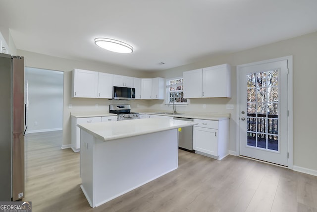 kitchen with a kitchen island, white cabinetry, sink, and appliances with stainless steel finishes