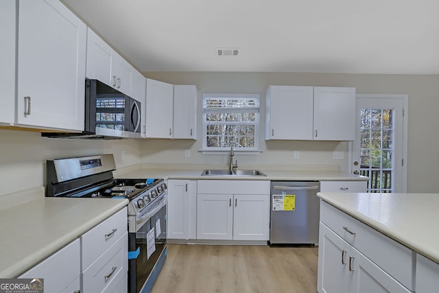 kitchen with white cabinets, a wealth of natural light, sink, and appliances with stainless steel finishes