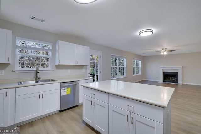 kitchen with sink, white cabinets, stainless steel dishwasher, and light wood-type flooring