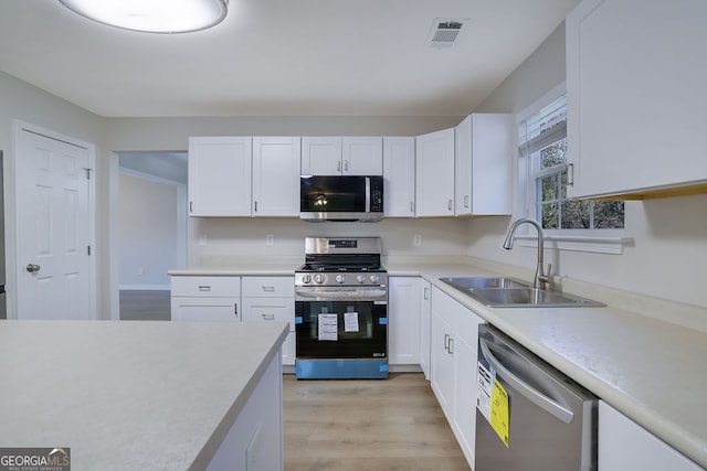 kitchen featuring white cabinets, stainless steel appliances, light hardwood / wood-style floors, and sink