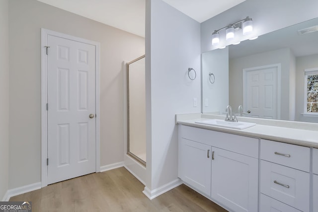 bathroom featuring hardwood / wood-style floors, vanity, and a shower with shower door