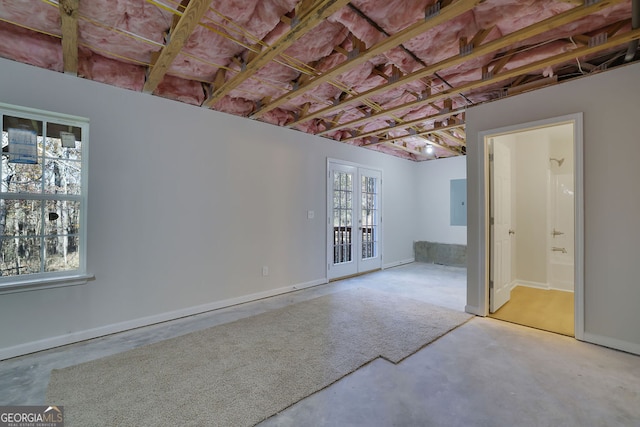 spare room with a wealth of natural light, french doors, and concrete flooring