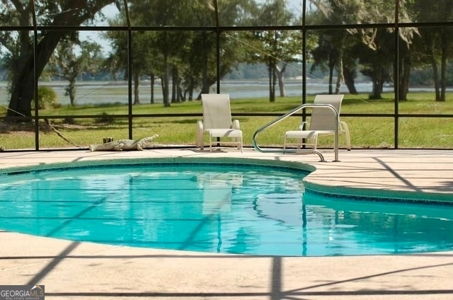 view of pool featuring glass enclosure, a patio area, and a yard