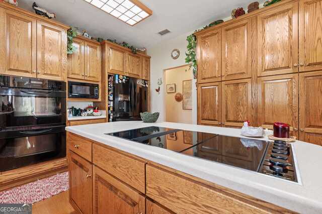 3917 Harris Neck Rd NE, Townsend, GA 31331 - kitchen featuring black appliances, light countertops, brown cabinets, vaulted ceiling, and wood finished floors