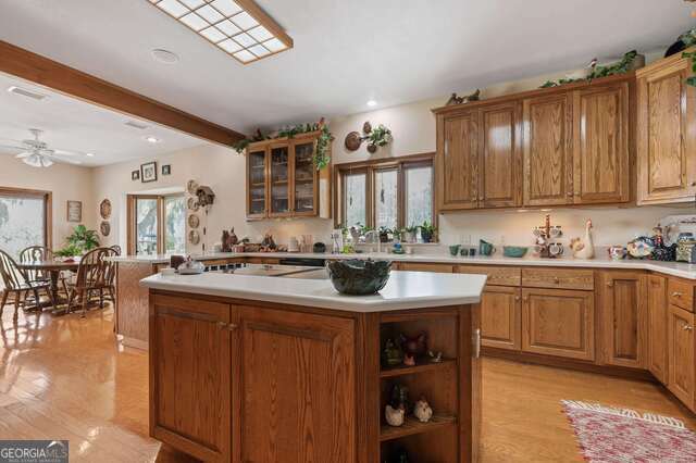 kitchen featuring beam ceiling, a center island, light hardwood / wood-style flooring, and ceiling fan