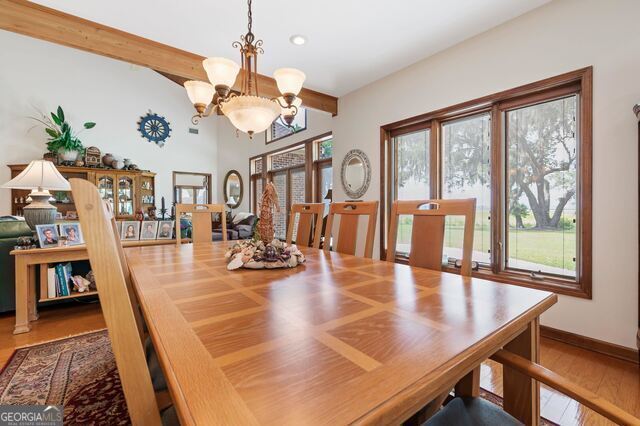 dining space with beam ceiling, wood-type flooring, and a notable chandelier