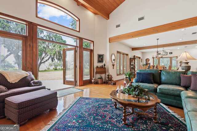 living room with beamed ceiling, a healthy amount of sunlight, light hardwood / wood-style floors, and high vaulted ceiling