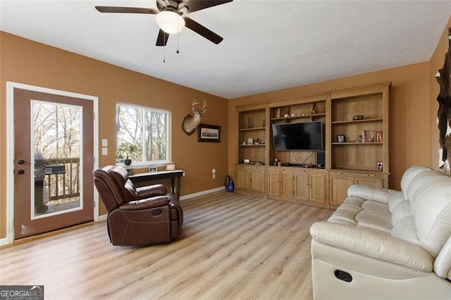 living room with baseboards, a ceiling fan, and light wood finished floors