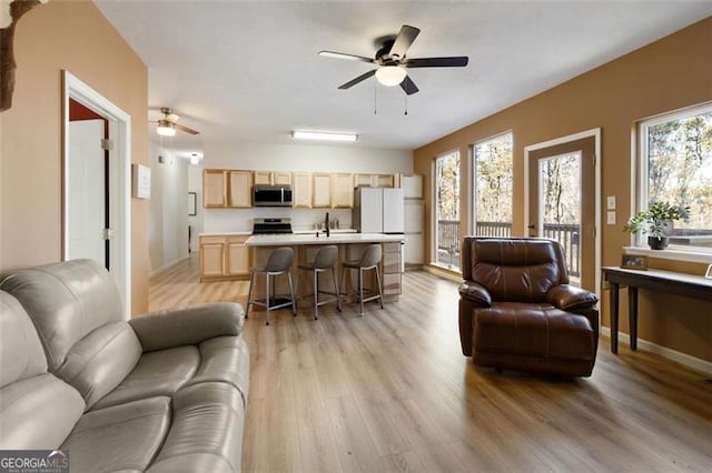 living area featuring baseboards, a ceiling fan, and light wood-style floors