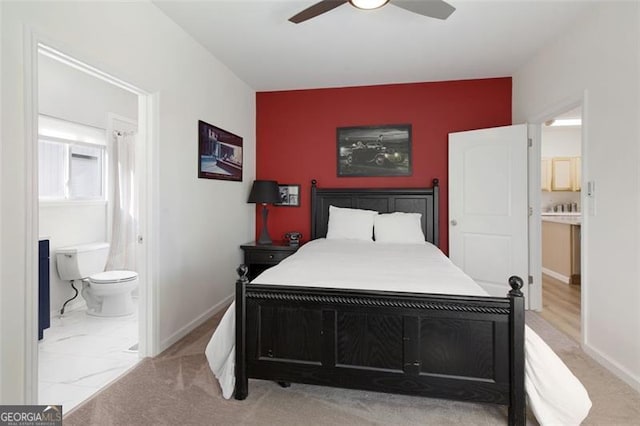 bedroom with ensuite bathroom, baseboards, an accent wall, and a ceiling fan