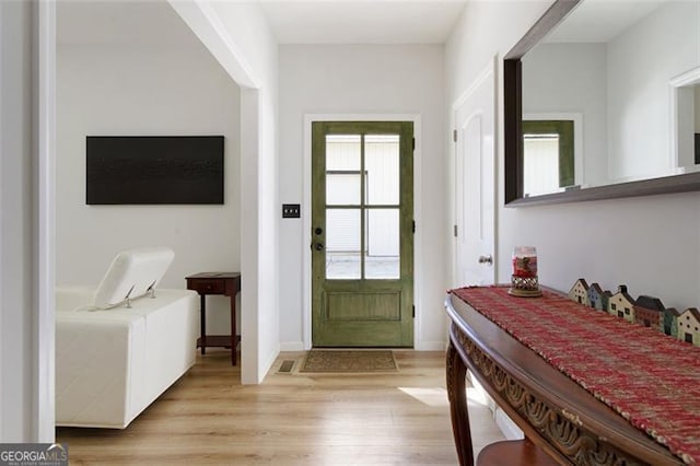 doorway to outside with light wood finished floors and baseboards