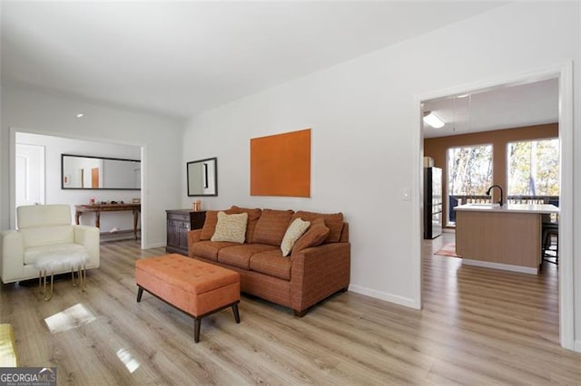 living area with light wood finished floors, attic access, and baseboards