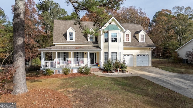 view of front facade featuring a porch, a front yard, roof with shingles, and driveway