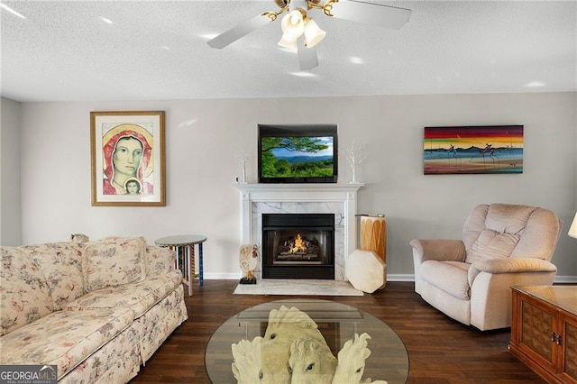 living area with a ceiling fan, a textured ceiling, wood finished floors, and a premium fireplace