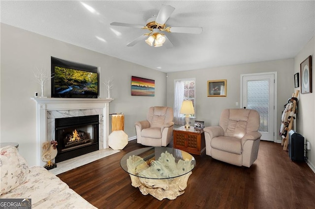 living room featuring a fireplace, wood finished floors, baseboards, and a ceiling fan