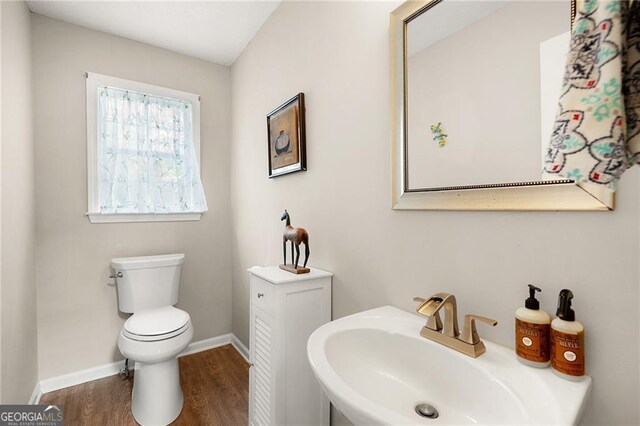 bathroom featuring toilet, wood finished floors, baseboards, and a sink