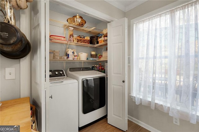 washroom with laundry area, crown molding, wood finished floors, and washing machine and clothes dryer