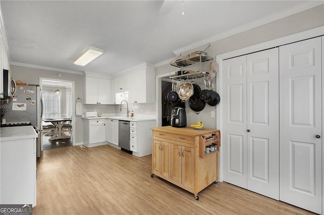 kitchen featuring crown molding, light wood-type flooring, light countertops, appliances with stainless steel finishes, and a sink