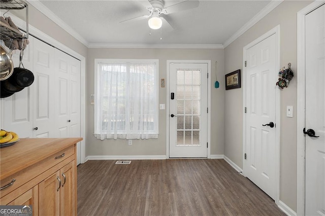 doorway with visible vents, ornamental molding, dark wood-style floors, baseboards, and ceiling fan