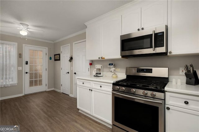 kitchen featuring dark wood-style floors, appliances with stainless steel finishes, white cabinets, crown molding, and light countertops