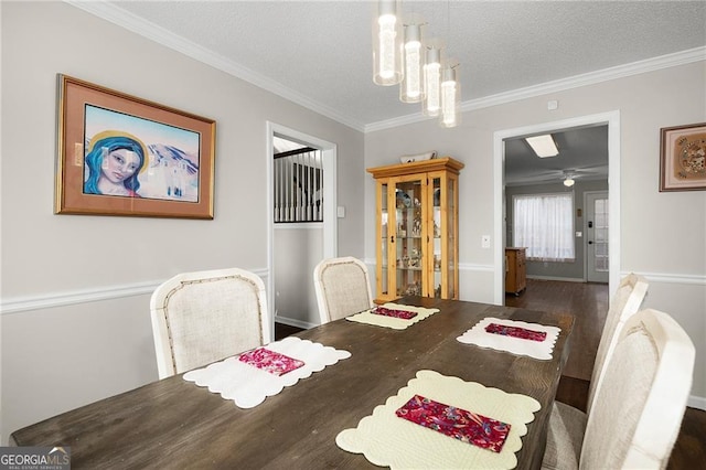 dining area featuring a textured ceiling, wood finished floors, crown molding, and ceiling fan with notable chandelier