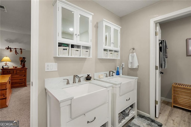 bathroom featuring a sink, visible vents, baseboards, and two vanities