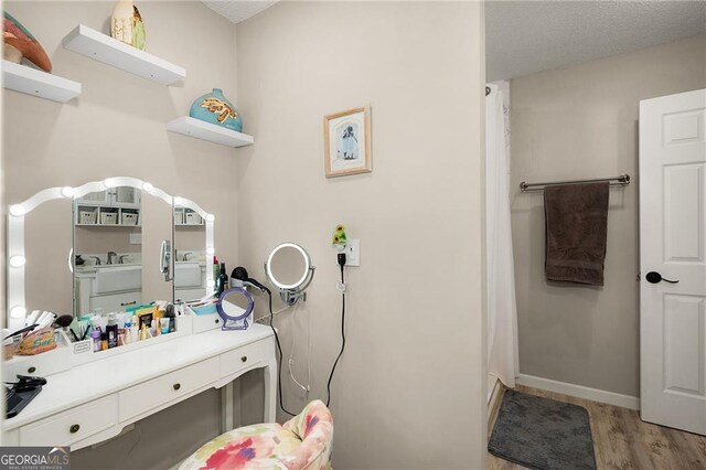 bathroom with vanity, wood finished floors, baseboards, a textured ceiling, and curtained shower