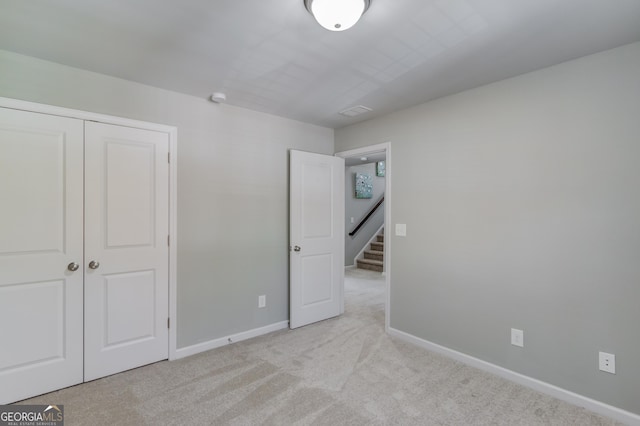 unfurnished bedroom featuring light colored carpet and a closet