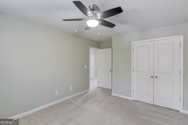 unfurnished bedroom featuring ceiling fan, light colored carpet, and a closet