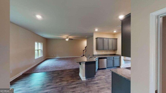 kitchen with dishwasher, dark wood-type flooring, sink, ceiling fan, and a kitchen bar