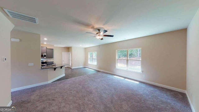 unfurnished living room featuring dark colored carpet and ceiling fan