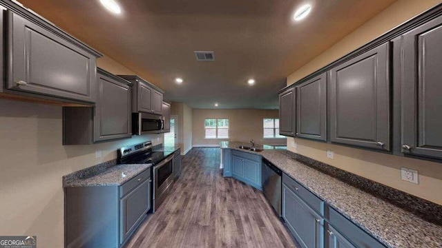 kitchen with gray cabinetry, sink, light hardwood / wood-style flooring, dark stone countertops, and stainless steel appliances