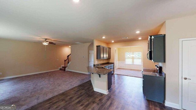 kitchen featuring ceiling fan, sink, dark wood-type flooring, and a breakfast bar area