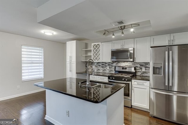 kitchen with sink, dark wood-type flooring, stainless steel appliances, a center island with sink, and white cabinets