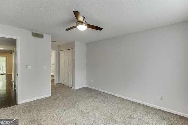 unfurnished bedroom with ceiling fan, light colored carpet, a textured ceiling, and a closet