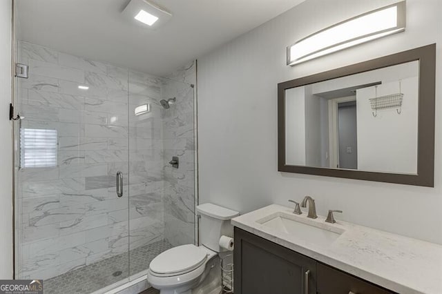 bathroom with vanity, a shower with shower door, and toilet