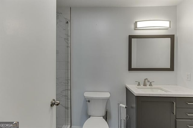 bathroom with toilet, vanity, and tiled shower