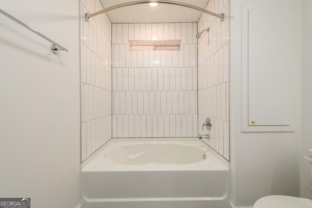 bathroom with toilet and tiled shower / bath