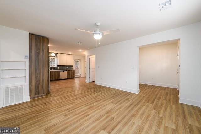 unfurnished living room featuring light hardwood / wood-style floors, built in features, ceiling fan, and sink