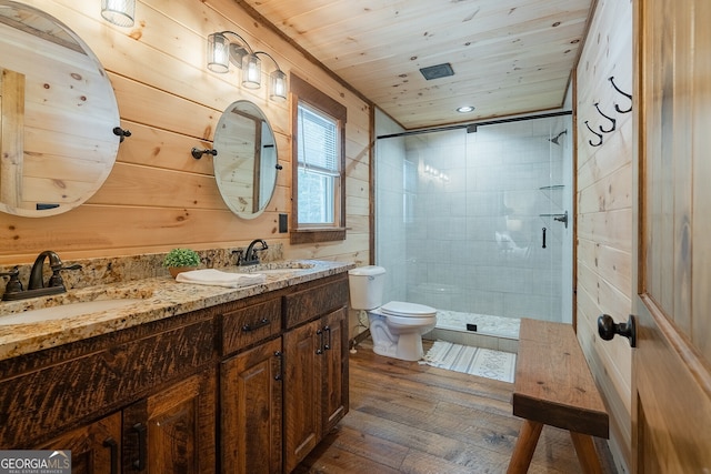 bathroom with tiled shower, hardwood / wood-style flooring, toilet, and wooden walls