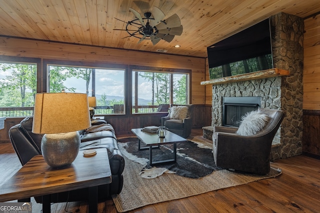 living room featuring a wealth of natural light, hardwood / wood-style floors, ceiling fan, and wood walls