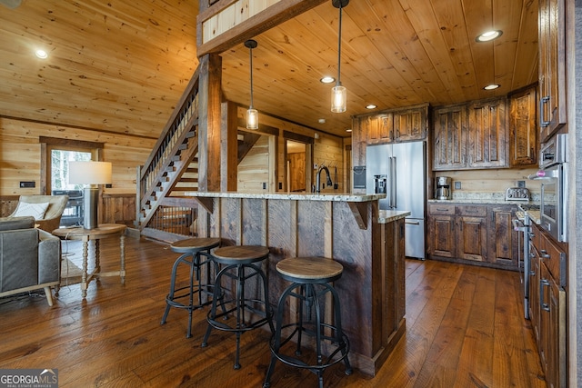 kitchen featuring wooden walls, dark hardwood / wood-style flooring, stainless steel appliances, and light stone counters