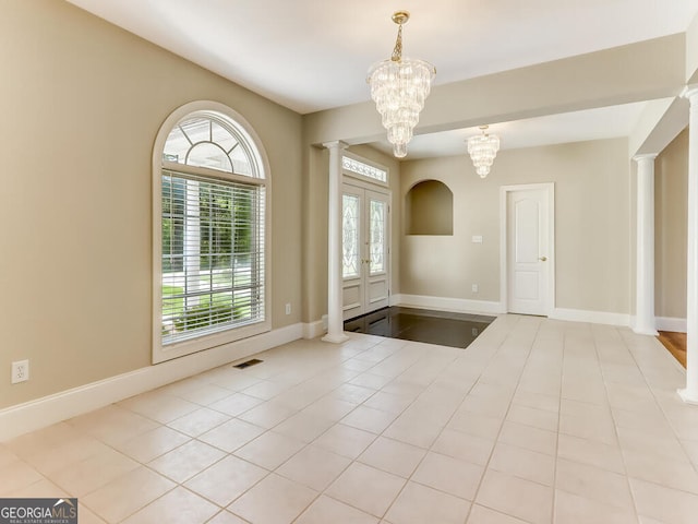 tiled entrance foyer featuring ornate columns, french doors, and a chandelier