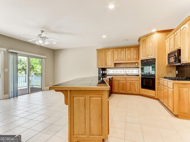 kitchen featuring ceiling fan, sink, black appliances, light brown cabinets, and tile counters